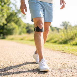 Adult walking outdoors wearing the knee strap below the kneecap